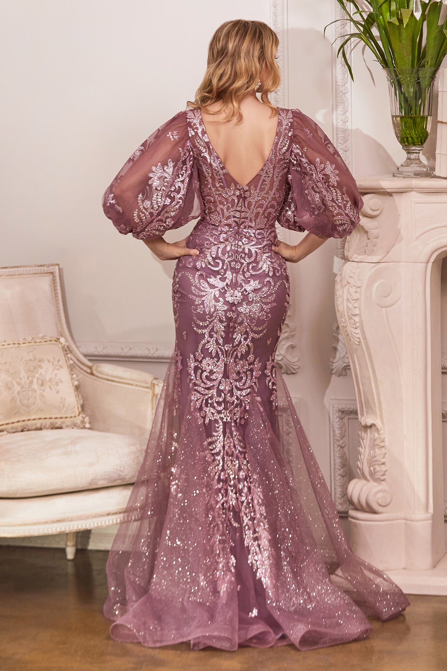 This mermaid beauty is embellished with metallic glitter and beaded scroll design. The puff three-quarter keyhole sleeve joins the boned corset sheer bodice. With a fitted under skirt the bottom overlay fans out with godets and trailing train Cinderella D
